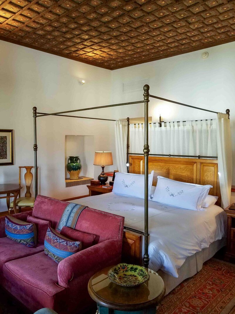 Elegant four-poster bed with embroidered linens and a carved wooden ceiling in a suite at Belmond Palacio Nazarenas, Cusco, Peru ©Stephanie Dosch | theViatrix Luxury Hotel Stays