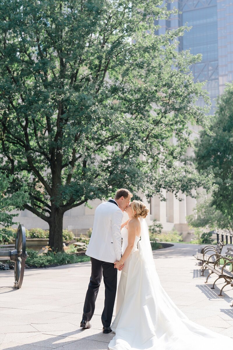Columbus wedding with bride and groom holding hands and kissing on a sideway in downtown as the sun illuminate their brides gown