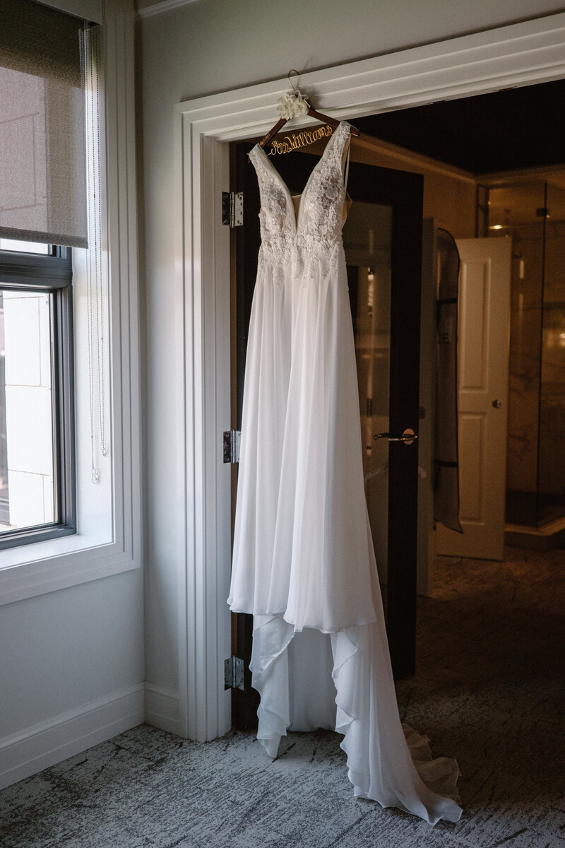 wedding dress hanging in door way on hanger