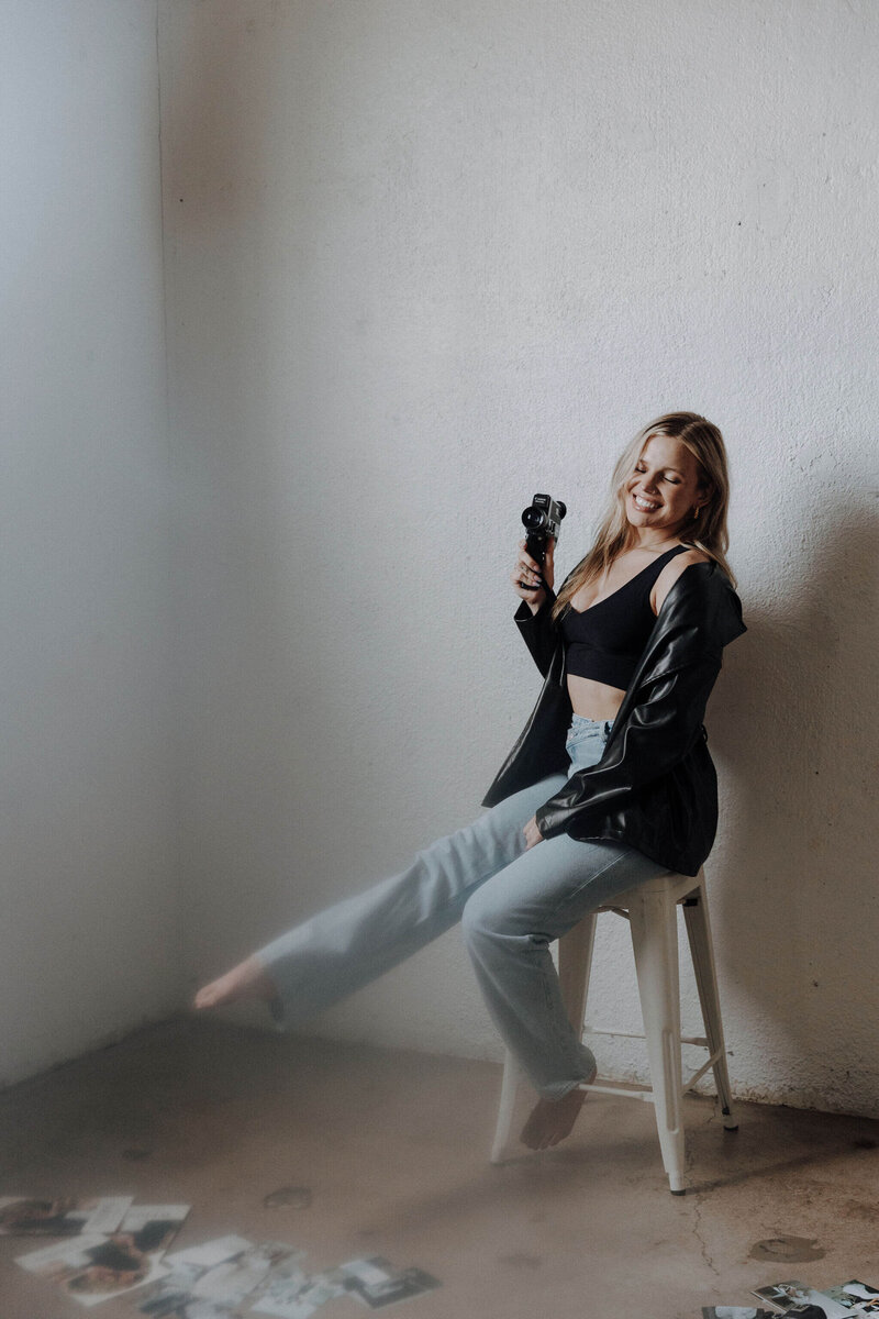 The-girl-is-sitting-on-a-chair-smiling-and-holding-a-camera