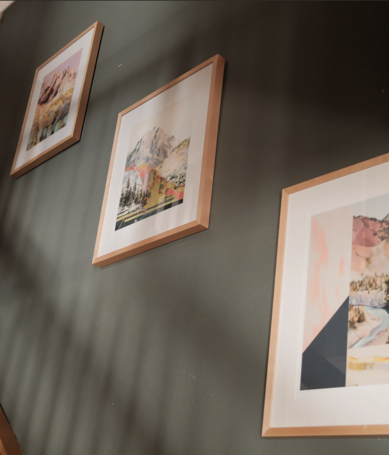 Three hanging pictures on a green wall