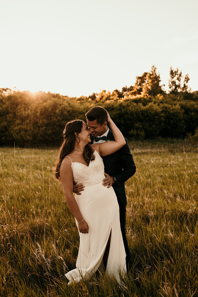 groom holding bride in sunset field