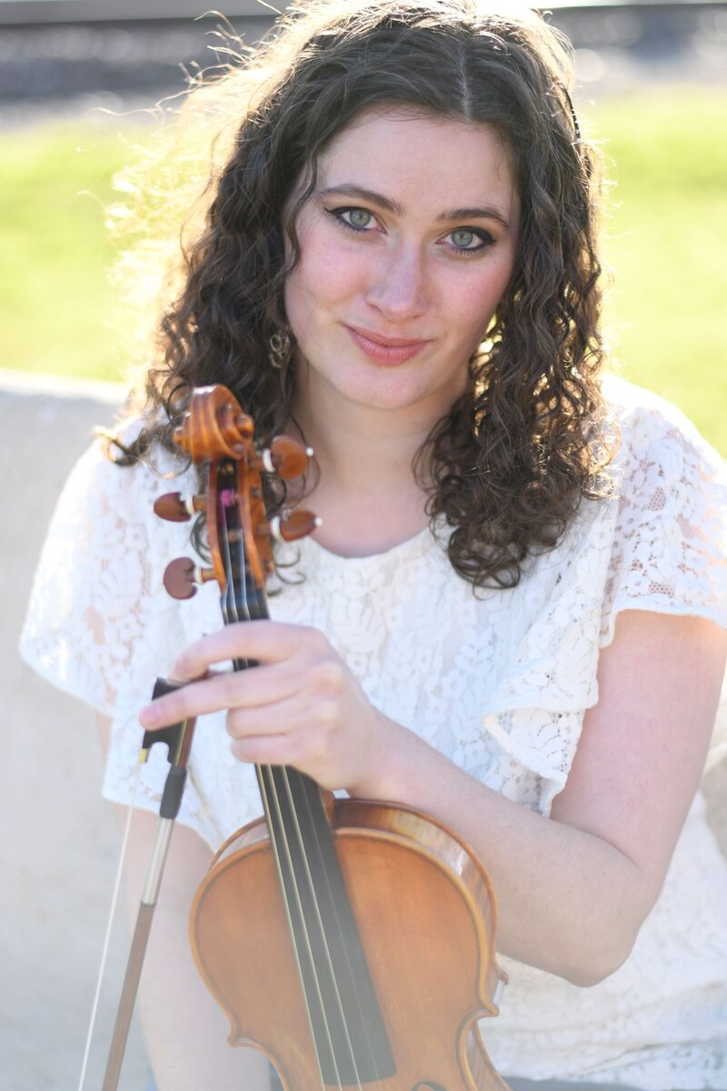 Seattle violin teacher Erika Burns sits on a bench with her violin.
