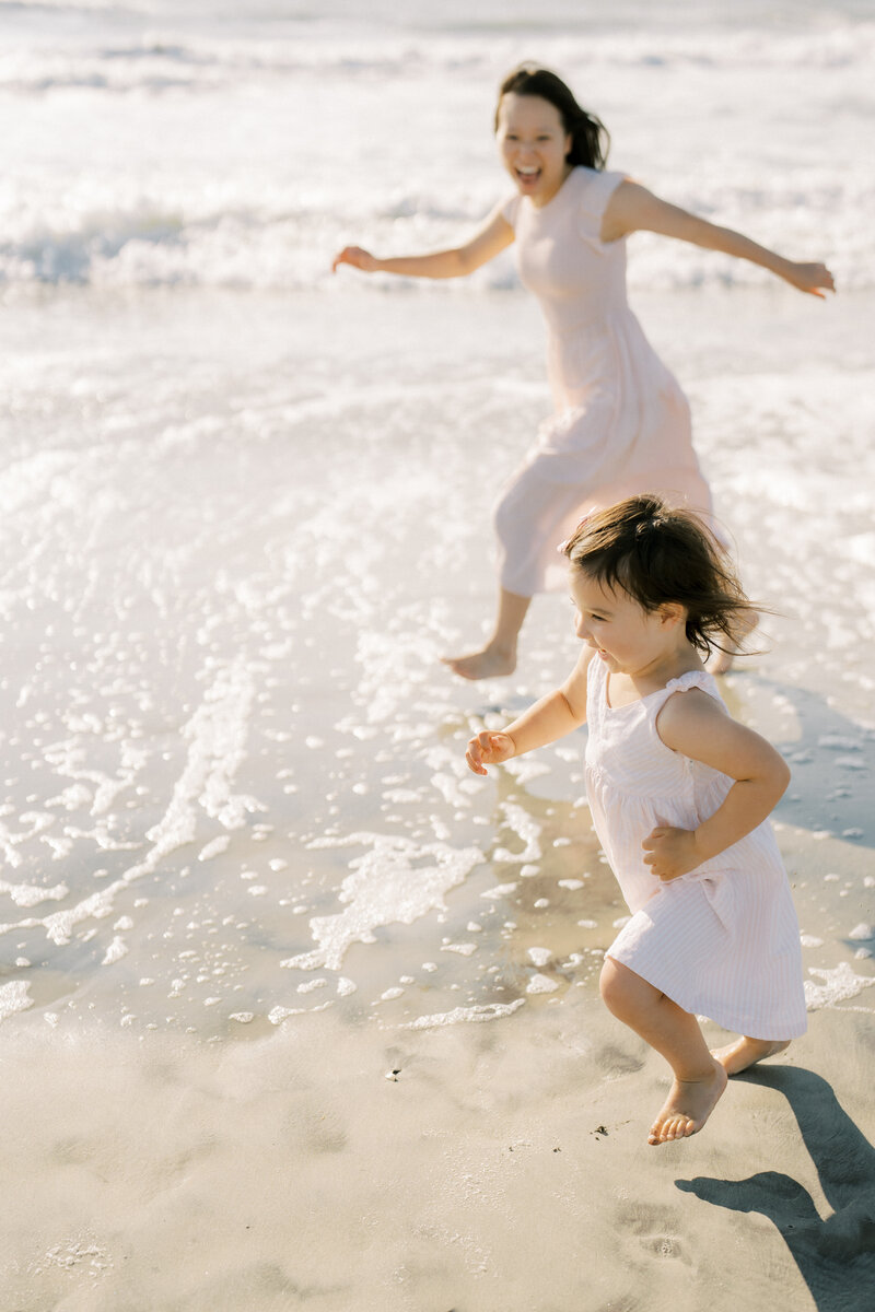 A mom and daughter running on the beach