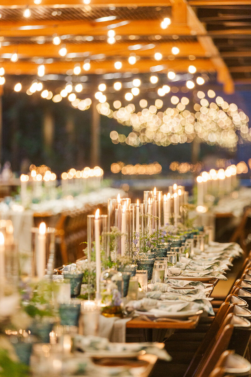 lots of ivory taper candled tablescape in a wedding reception room with bistro lights