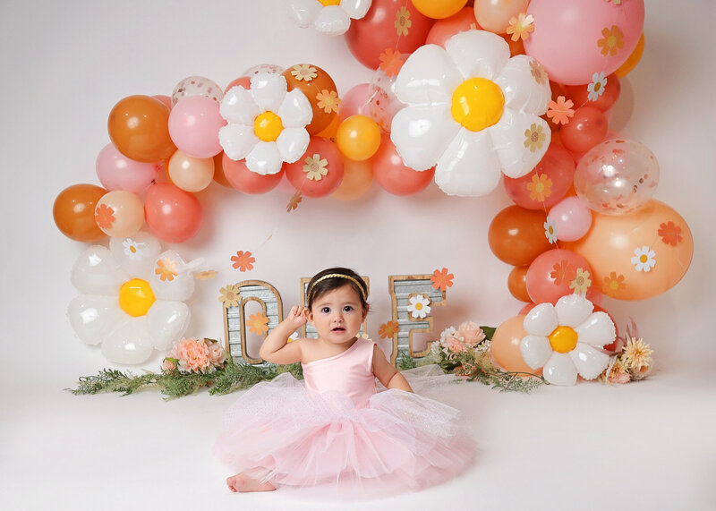 Sweet 1 year session posing in front of her blush floral set up.