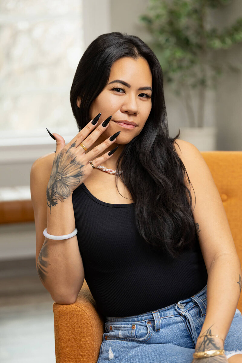 Woman nail tech sitting on couch during branding session with Sara Vaz in Utah.