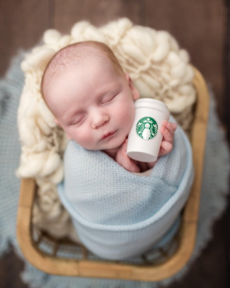 Baby boy wrapped in blue with a mini Starbucks cup—adorable newborn session with personality in Paris, Ontario.