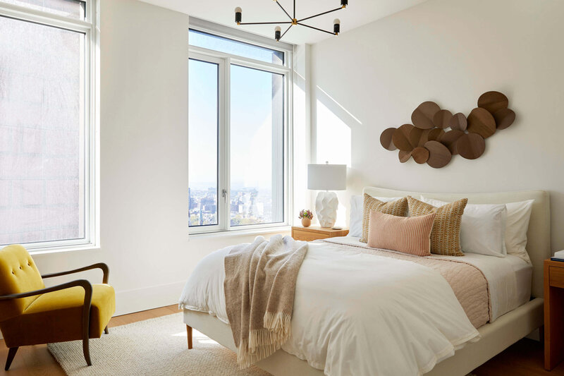 Neutral white, creams and brown bedroom with wooden art piece above bed frame and natural lighting.