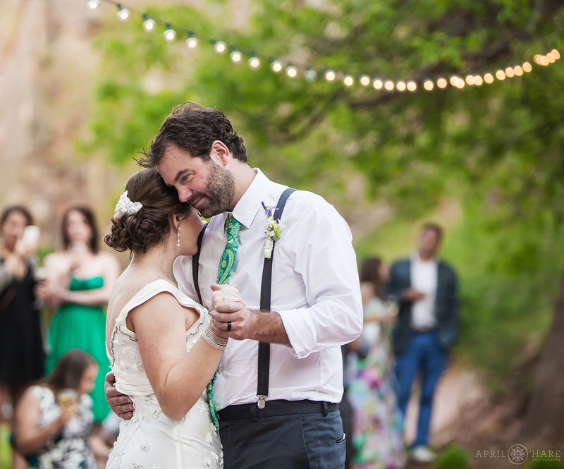 Bride and Groom dance on the flagstone patio under string lights at Riverbend in Lyons Colorado