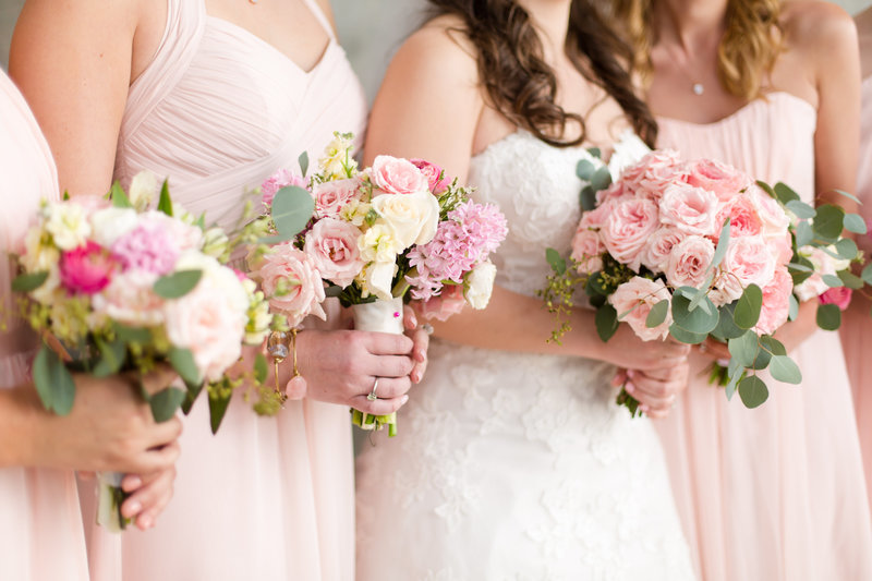 Bride and bridesmaids hold pink peony bouquets
