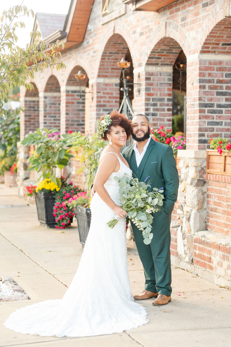 Smiling bride and groom pose outside the century room at grbic events in st. louis