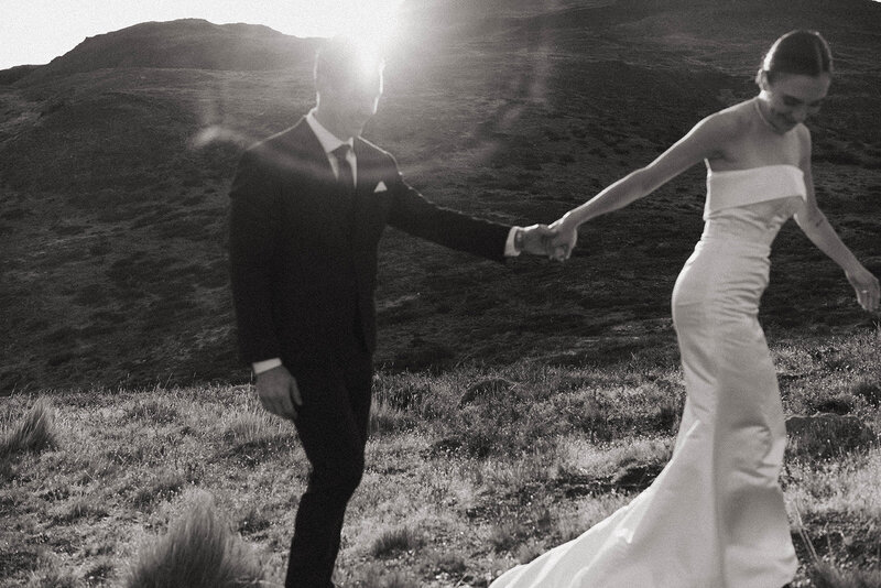 Bride and groom walking hand in hand through the mountains at golden hour, captured by a Washington elopement photographer.