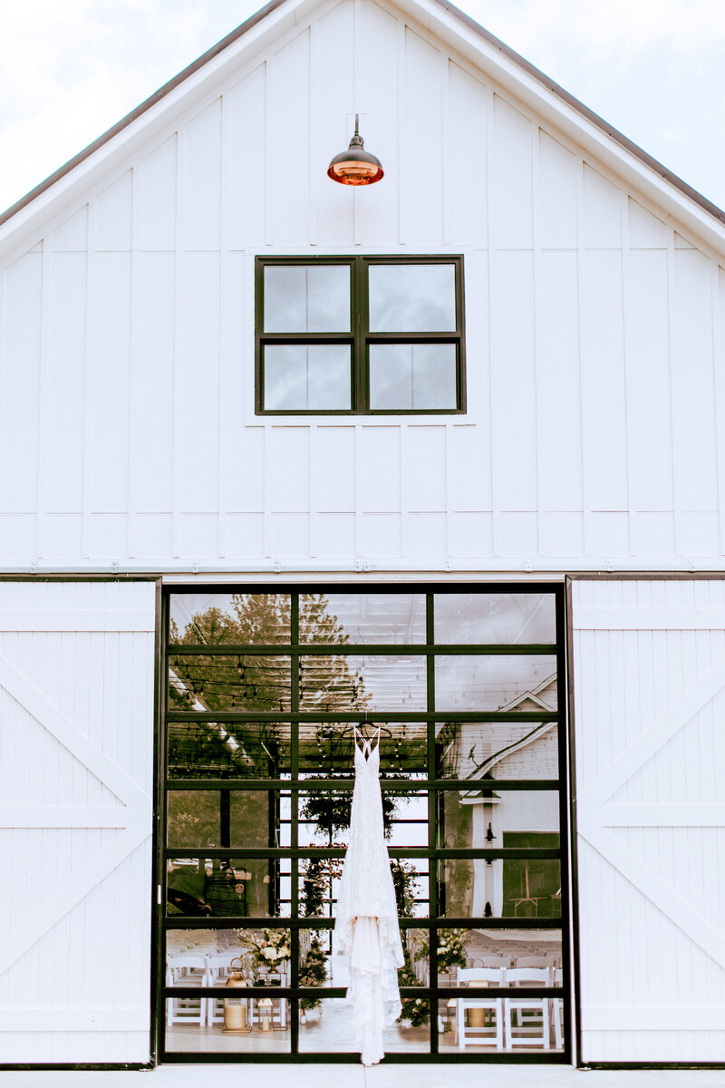 The front of White Barn with a dress hanging above the barn doors.
