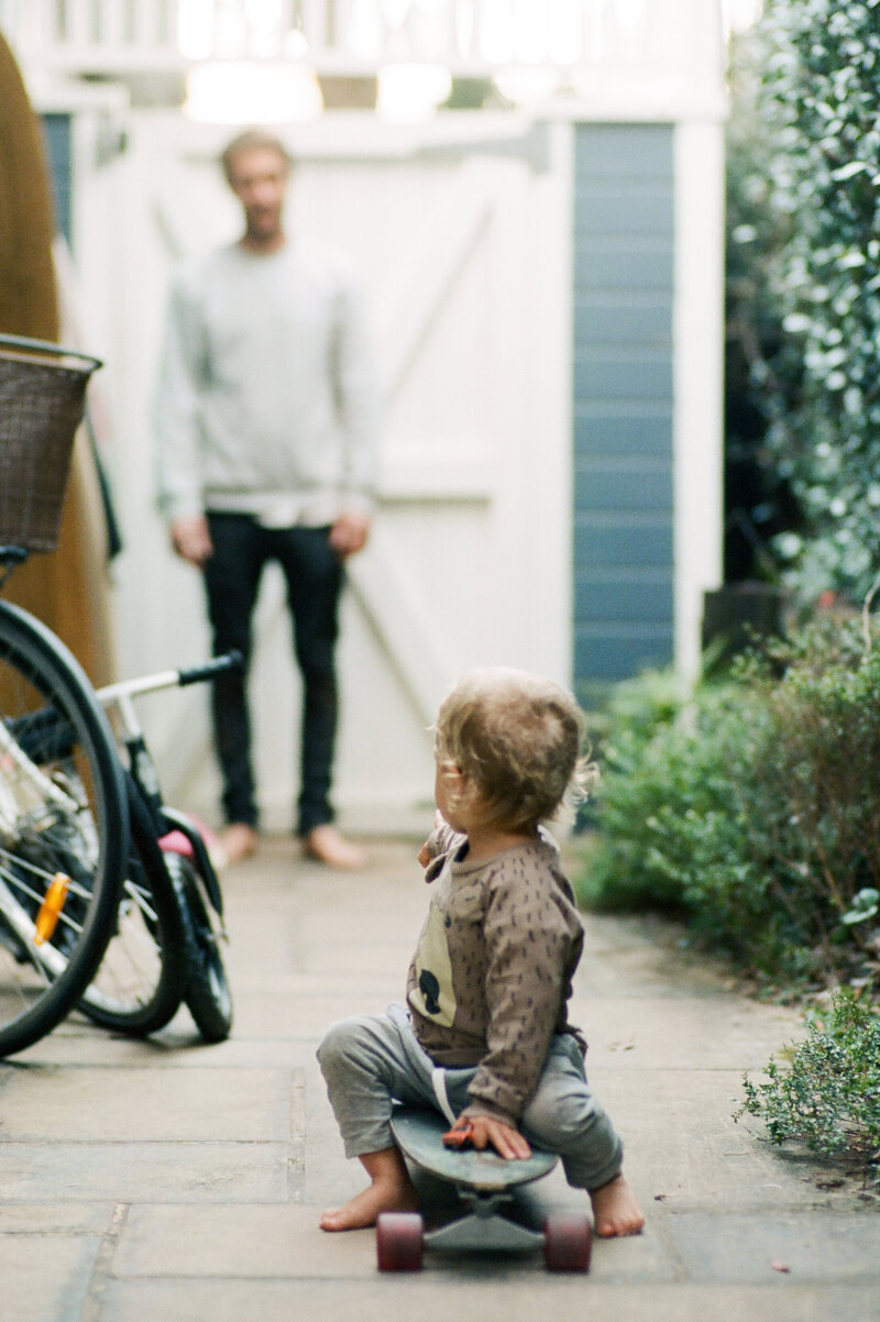 Young child sitting outside near a bicycle, a relaxed family photoshoot in Sydney