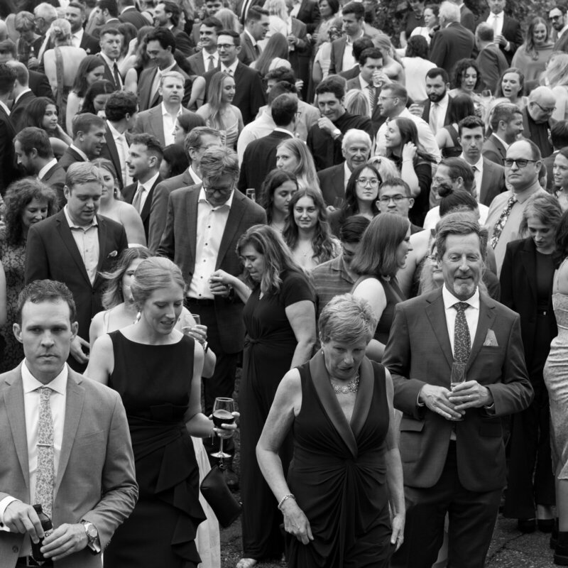 black and white image of wedding guests gathered in a crowd outside taken by minnesota wedding photographer tom thornton