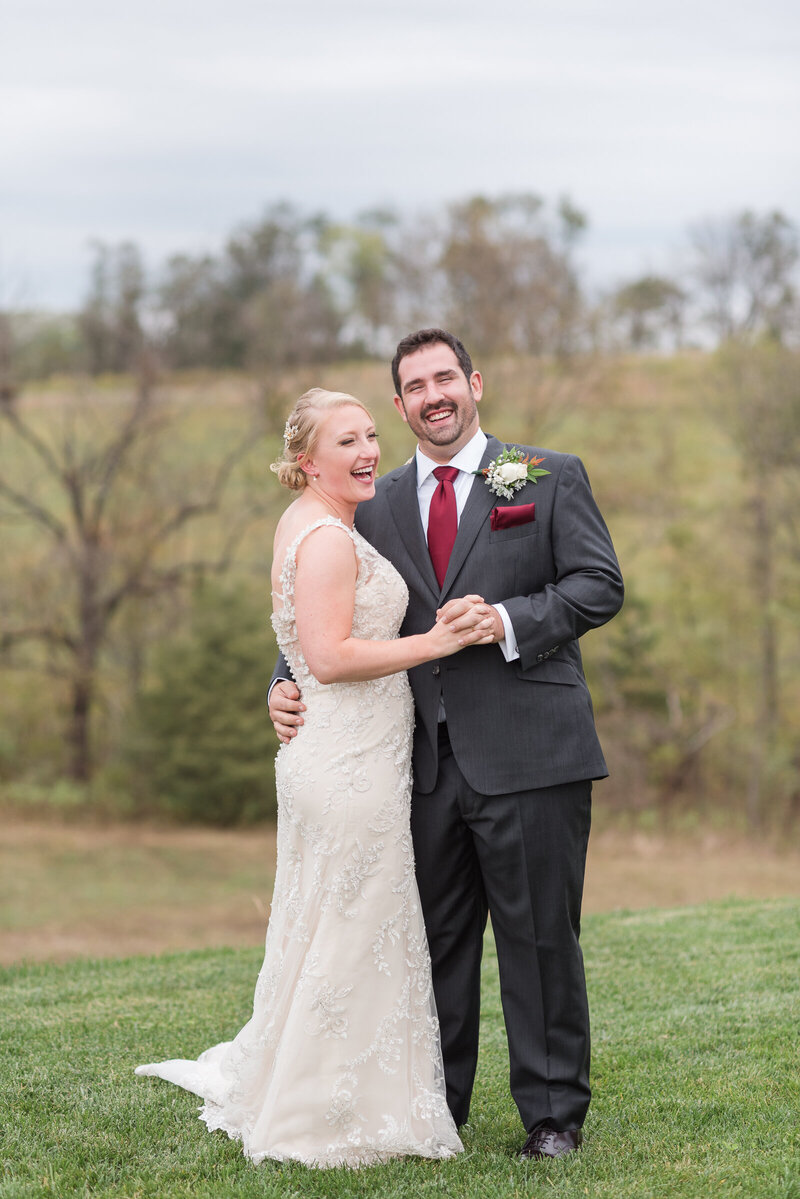 Bride and Groom Laughing and having their portrait taken in a field of green grass photographed by Austin TX based wedding photographer Lydia Teague