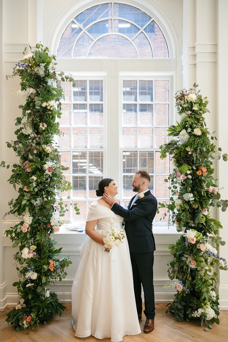 Portrait of bride and groom in between altar floral arrangements at Nashville wedding ceremony