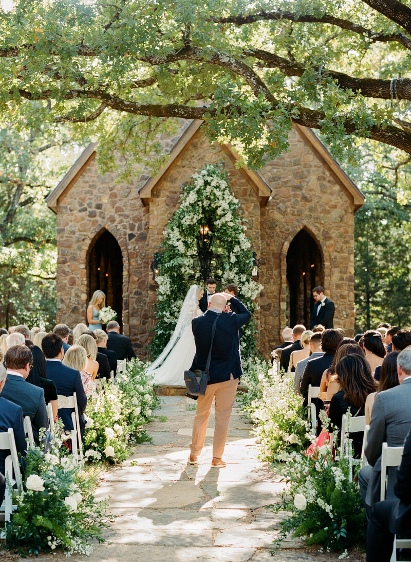 Jeff Brummett Photographing wedding ceremony in front of stone chapel outdoors