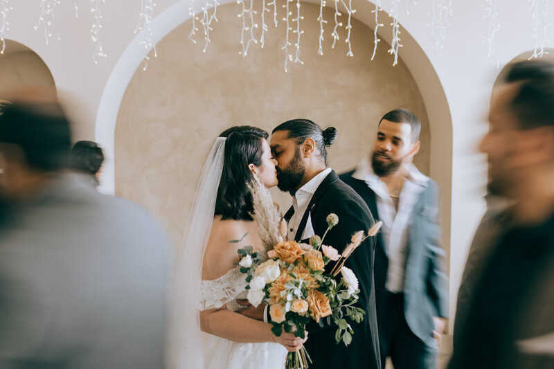 A bride and groom exchanging a kiss at their wedding ceremony.