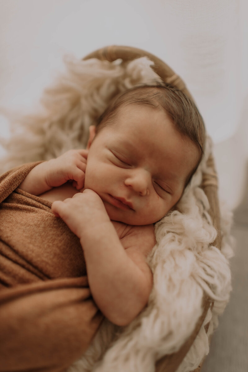 Baby slaapt in mandje tijdens newborn fotoshoot