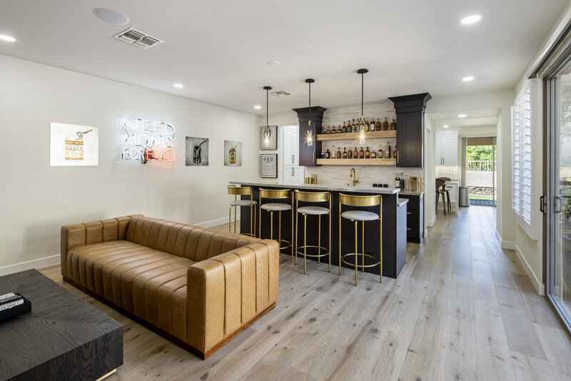 Remodeled bar by Renovation Inc. Engineered hardwood floor, marble countertops and black cabinets.