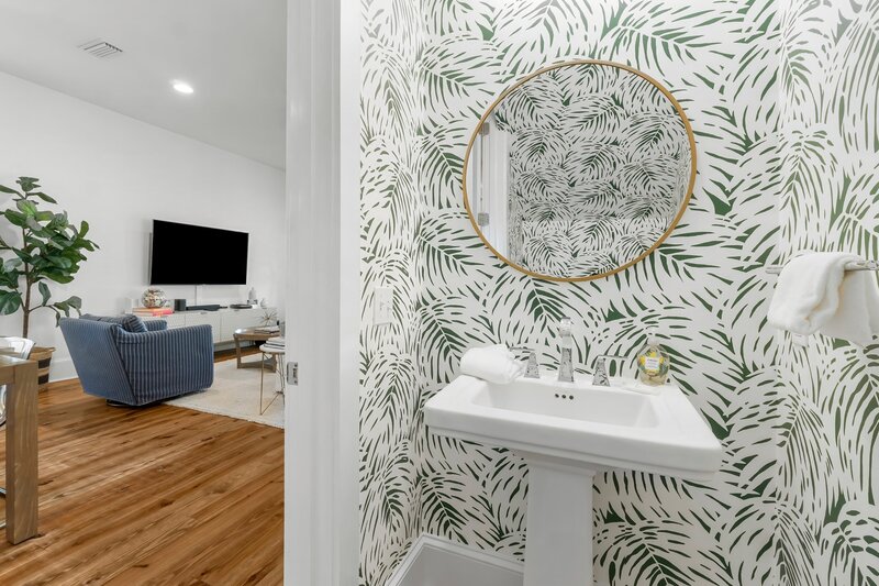 Chic half bath with bold palm print wallpaper, perfect for guests at this Panama City Beach vacation rental.
