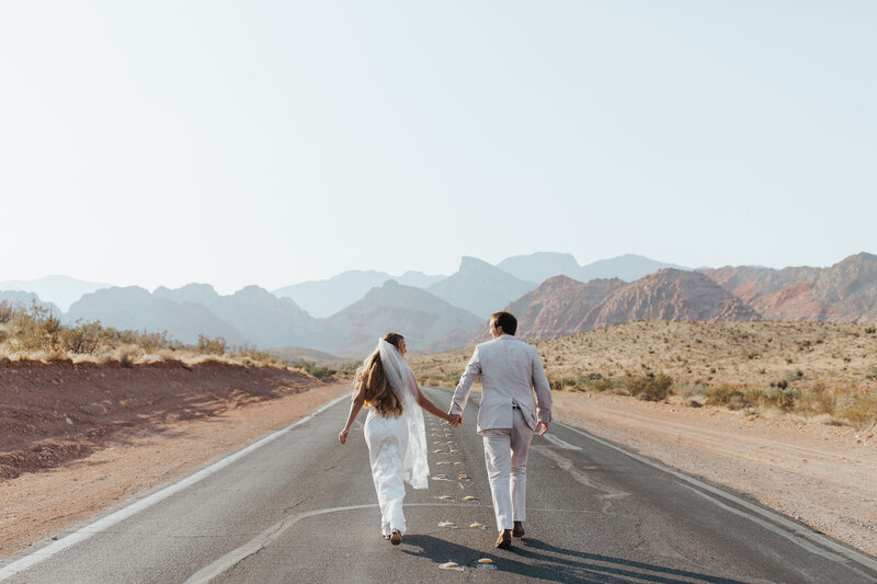 bride and groom run down road