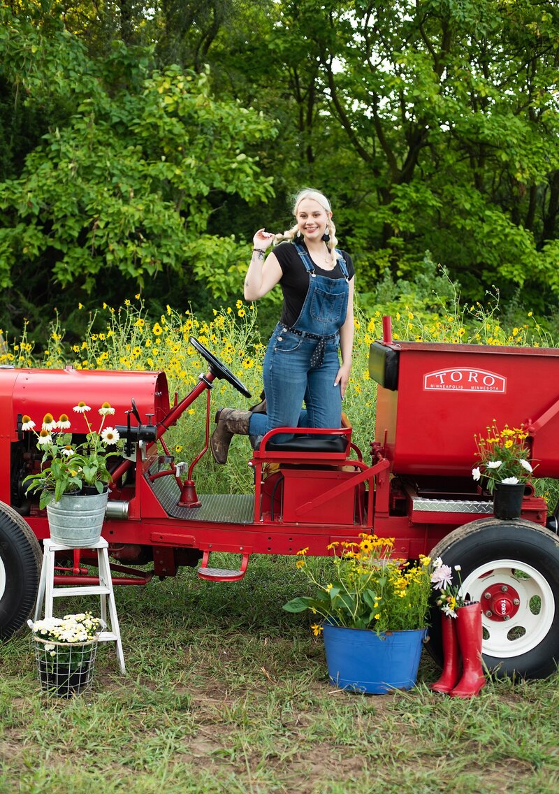 high school senior pictures farm themed shoot girls dreessed in ovralls posing with red tractor