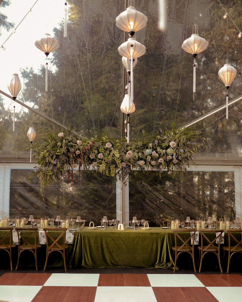 A wedding with hanging lanterns, floral design and green linens, representing the work of Eugene wedding planners Birdie June. 