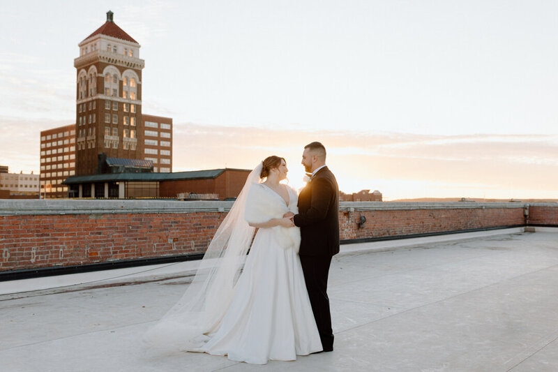 A bride and groom together on a rooptop.