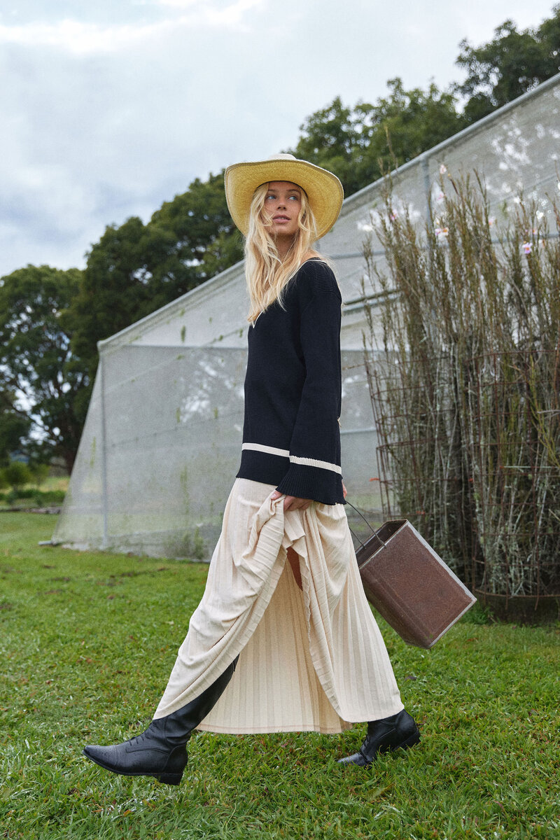 Model in white skirt and knit strolling through farm