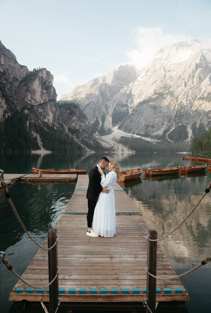 Bride and groom touch foreheads on a dock on an alpine lake during their hiking elopement