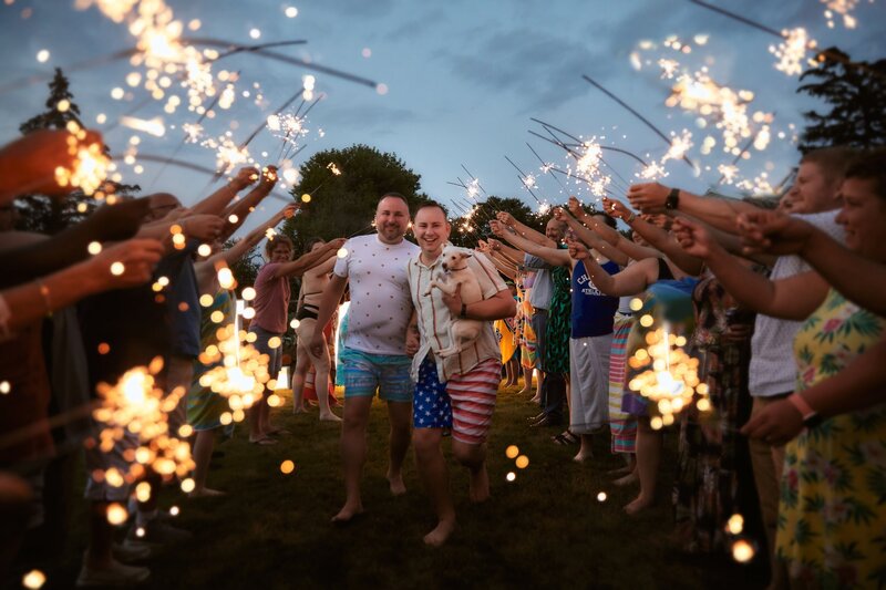 grooms walking with guests on either side holding sparklers
