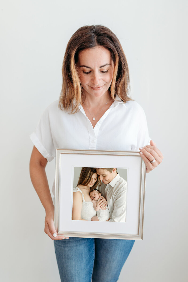 Atlanta Photographer Lisa Lefevre is holding  a framed family portrait taken in her studio.