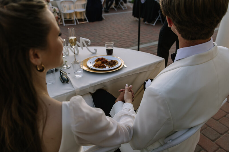 Payton looking at Evan while holding hands during the speeches at their wedding reception in Riverside.