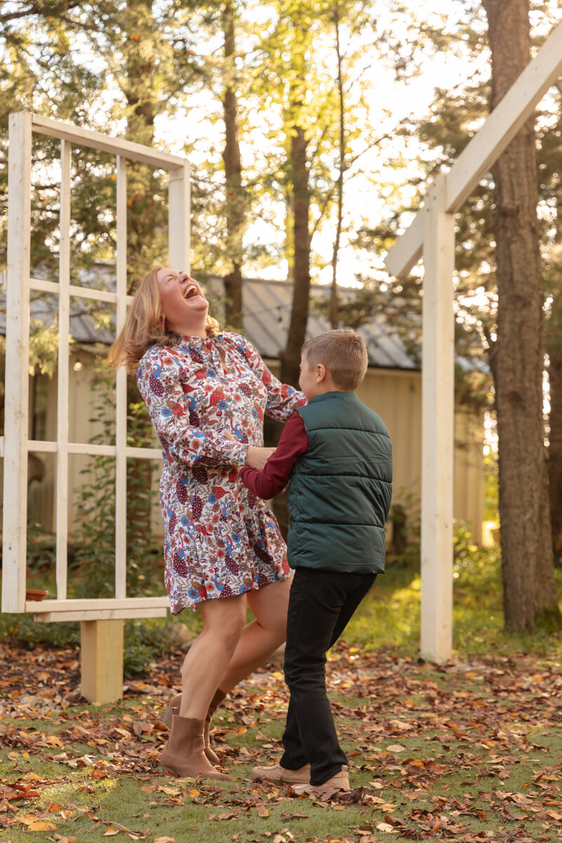 mother and son dance and laught at Rustic Wild Arrow outdoor chapel in fall