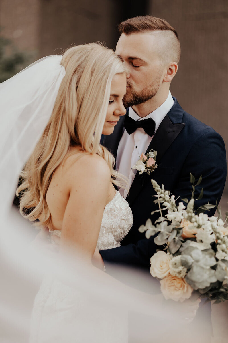 Groom in navy suit kissing bride