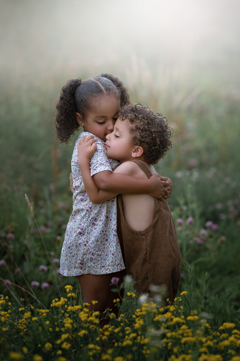 Siblings hugging in a flower field on a cloudy day by Iya Estrellado, a Virginia Beach children photographer.