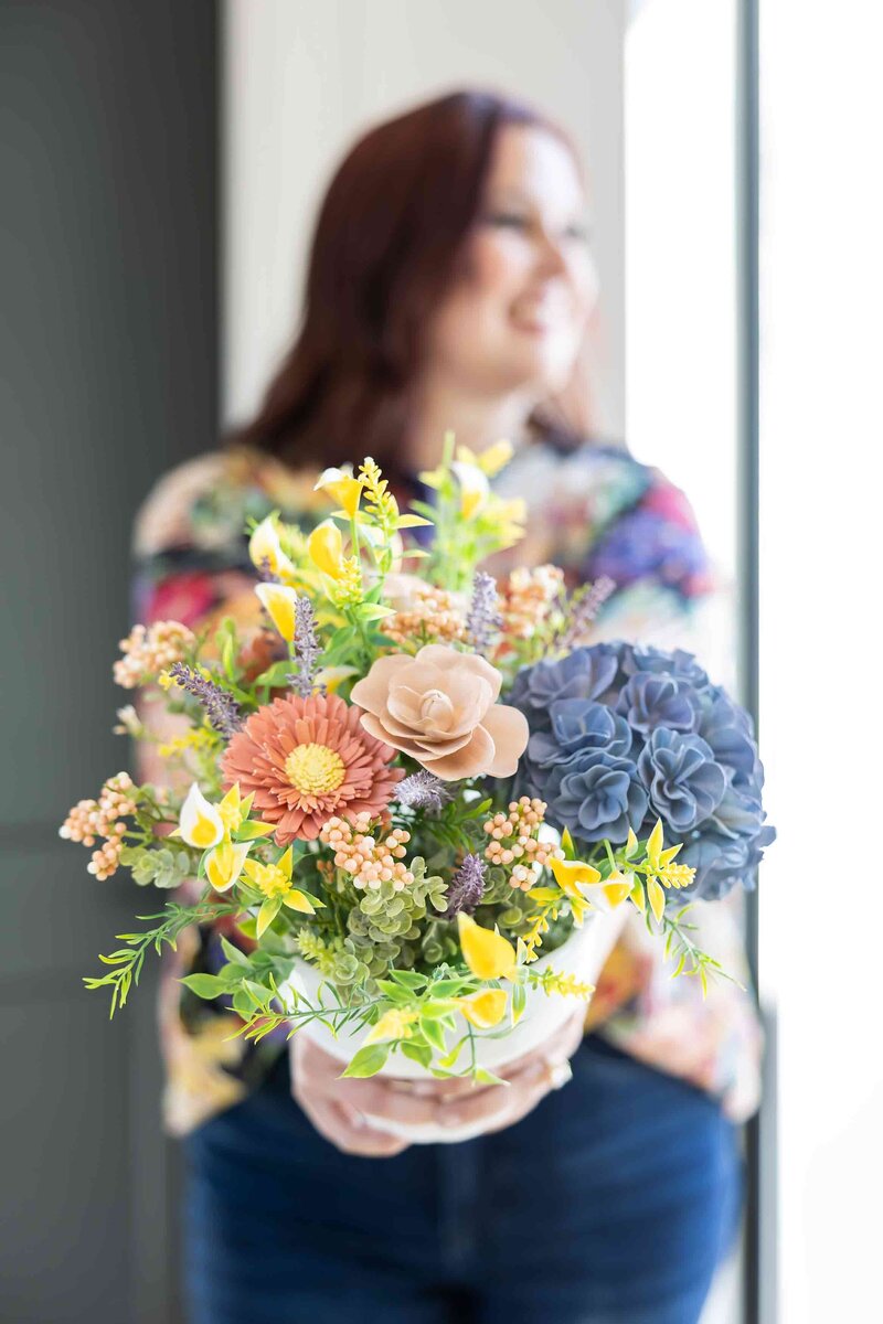 Strategic brand photography for online businesses featuring a female entrepreneur holding a bouquet of flowers, captured for a professional branding gallery.
