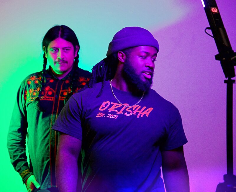 Two people at a photoshoot lit by purple and green lighting 