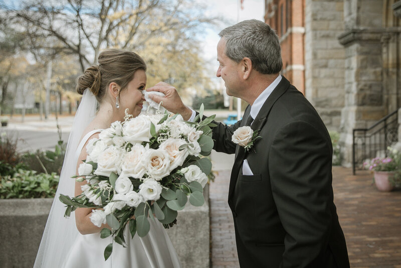 Father of the bride wiping her tears after their first look. Church in Detroit Michigan.
