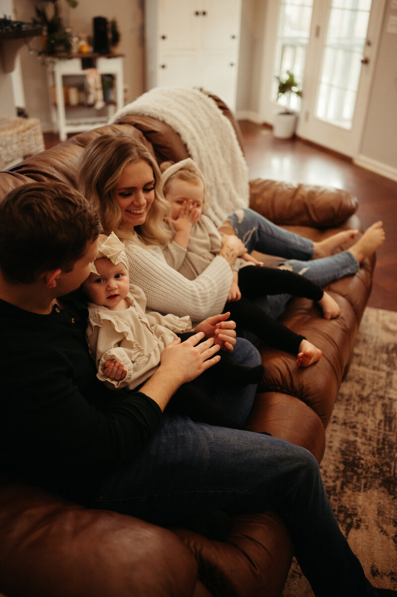 Family of four snuggling on the sofa.