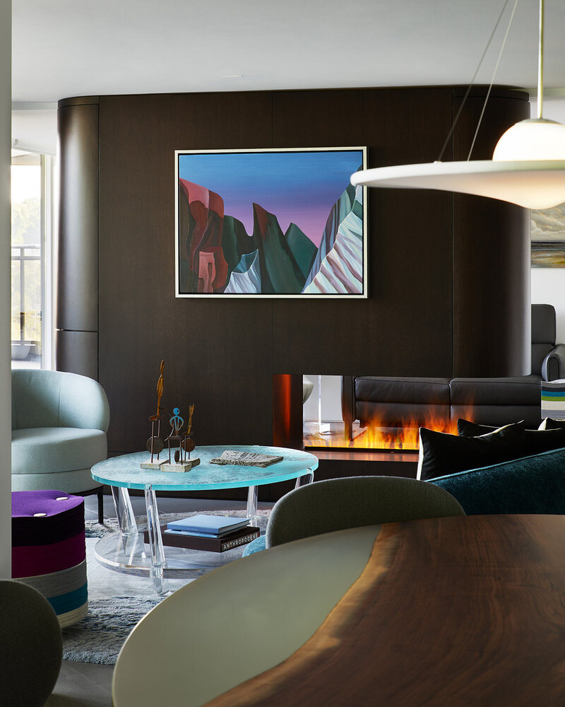 A minimalistic  condo living room featuring plush couches, a fireplace, and fine artwork