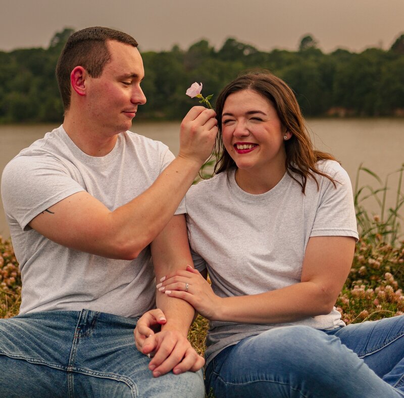 man tucking flower into his fiance's hair at couples photoshoot in oklahoma city