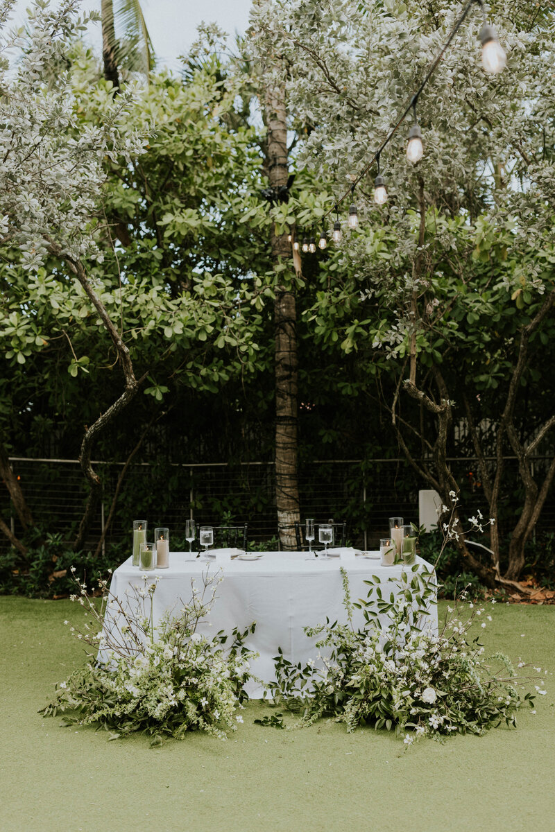 Head table of their wedding surrounded by large floral installations on the ground.