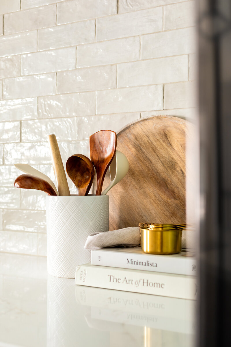 Kitchen utensils, cookbooks, and trays displayed next to stove top on counter.