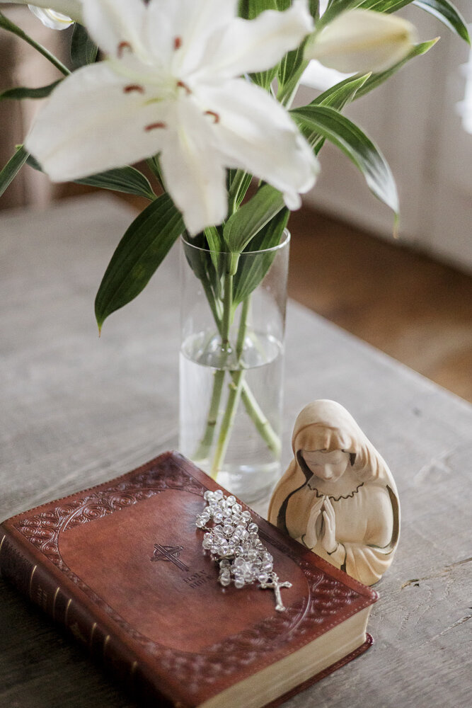 a Bible and white lily flower on a table