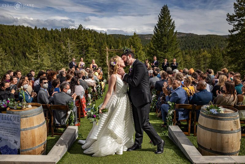 Couple Kiss as they Leave their Outdoor Wedding Ceremony at The Woodlands in Colorado