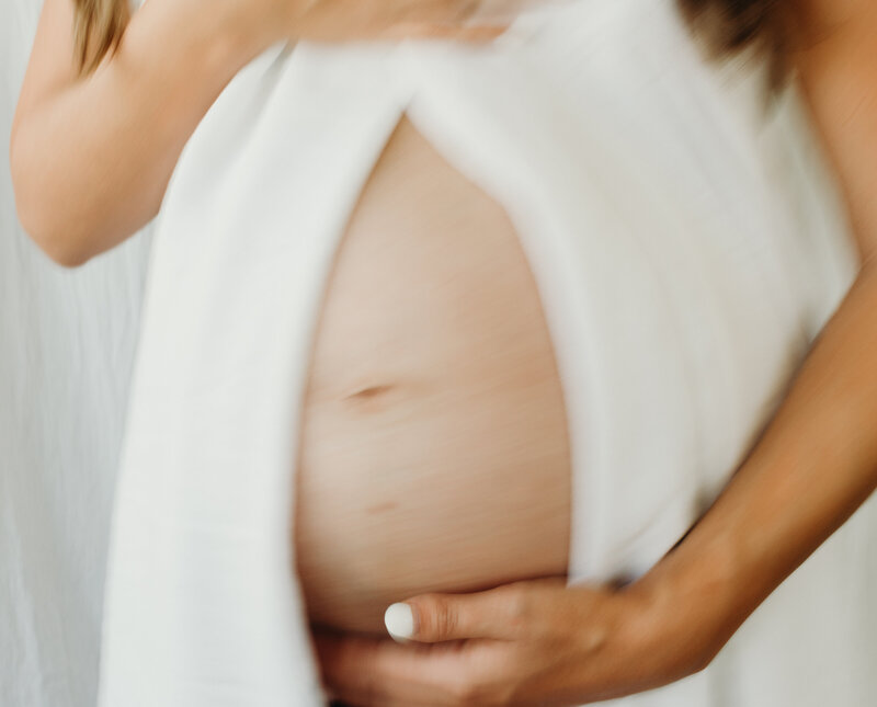 belly bump silhouetted against a white sheet in the sunset